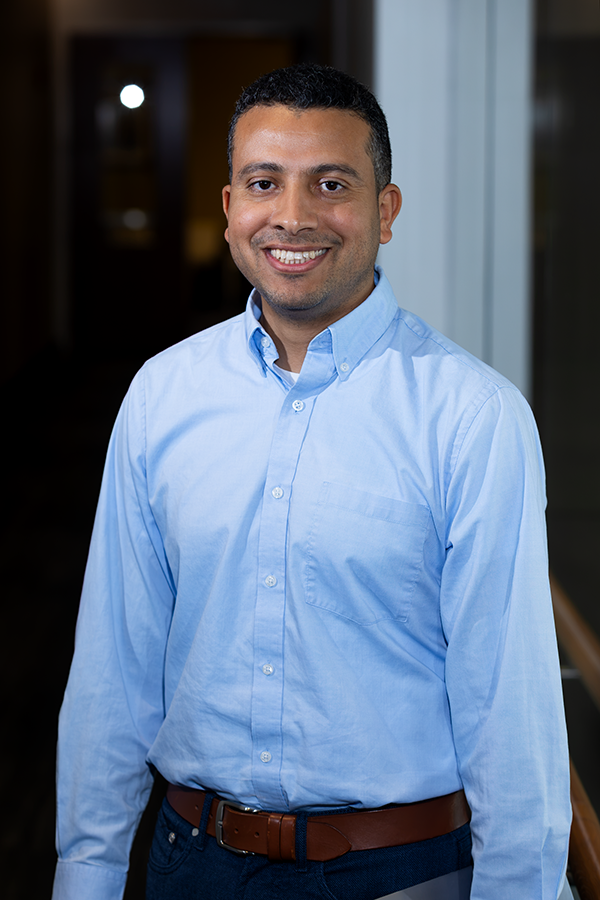 A man standing in a hallway of a modern research building.