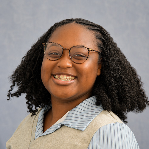 Woman poses for photo in front of backdrop.