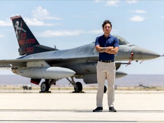 A man standing with his arms crossed in front of an airplane.