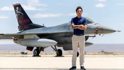 A man standing with his arms crossed in front of an airplane.