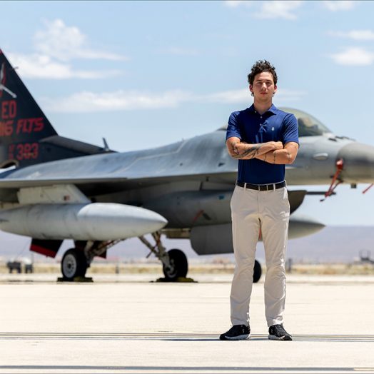 A man standing with his arms crossed in front of an airplane.
