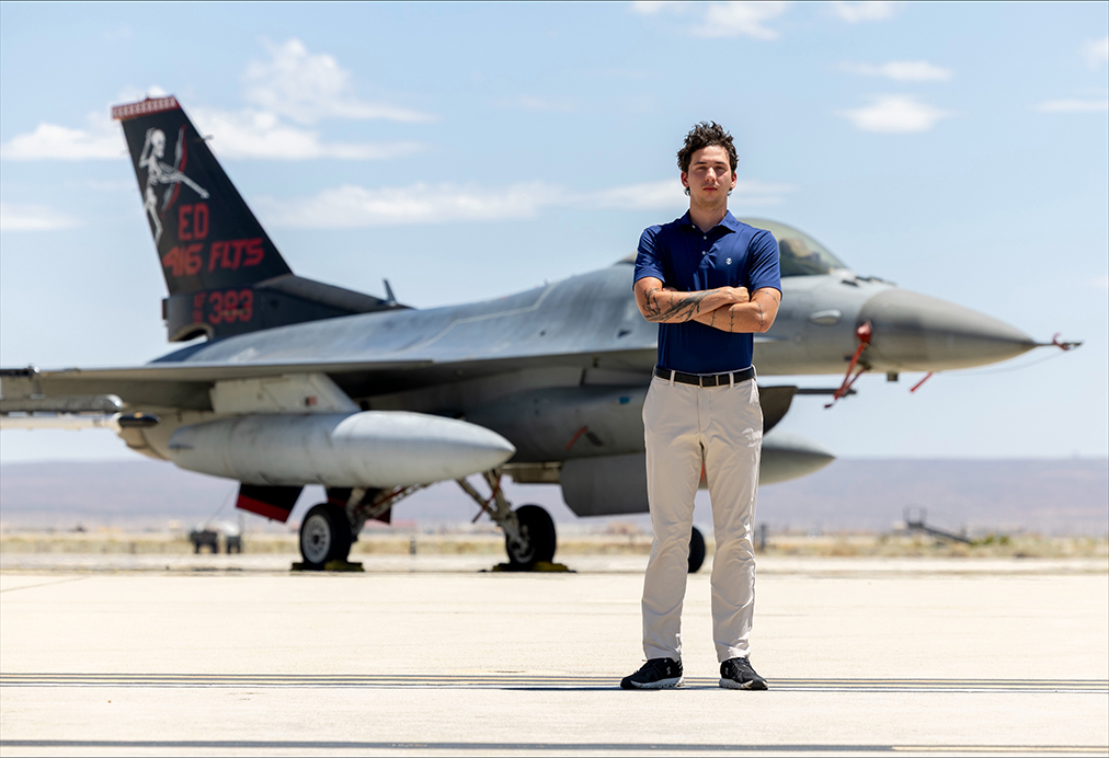 A man standing with his arms crossed in front of an airplane.