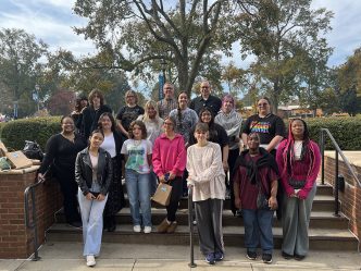 Stan Dodson, EdD, poses in front of University Hall with art students