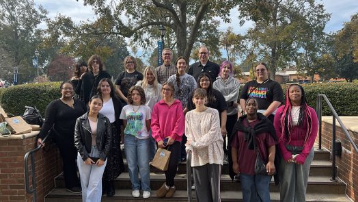 Stan Dodson, EdD, poses in front of University Hall with art students
