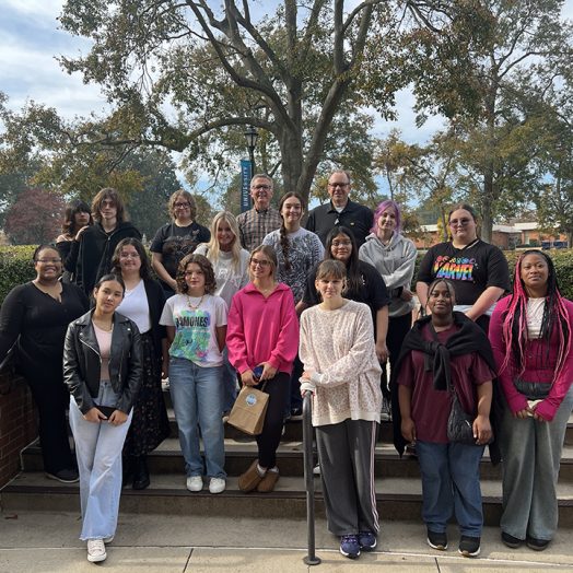 Stan Dodson, EdD, poses in front of University Hall with art students