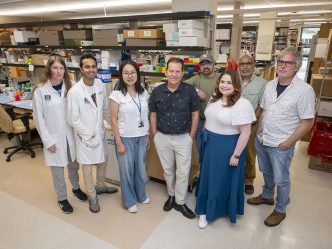 A group of people stand in front of lab equipment