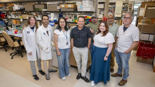 A group of people stand in front of lab equipment