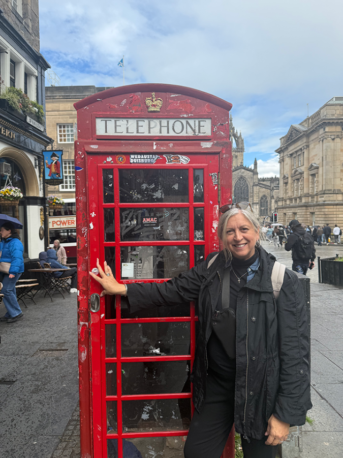 A woman with her arm on a telephone booth.