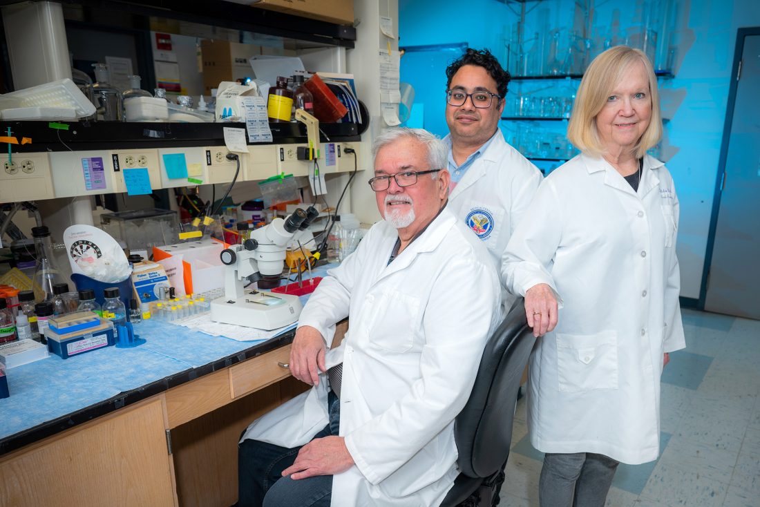 Two men and a woman standing in a lab