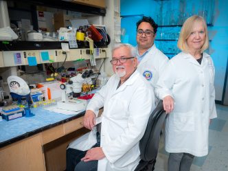 Two men and a woman standing in a lab