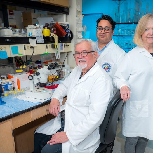 Two men and a woman standing in a lab