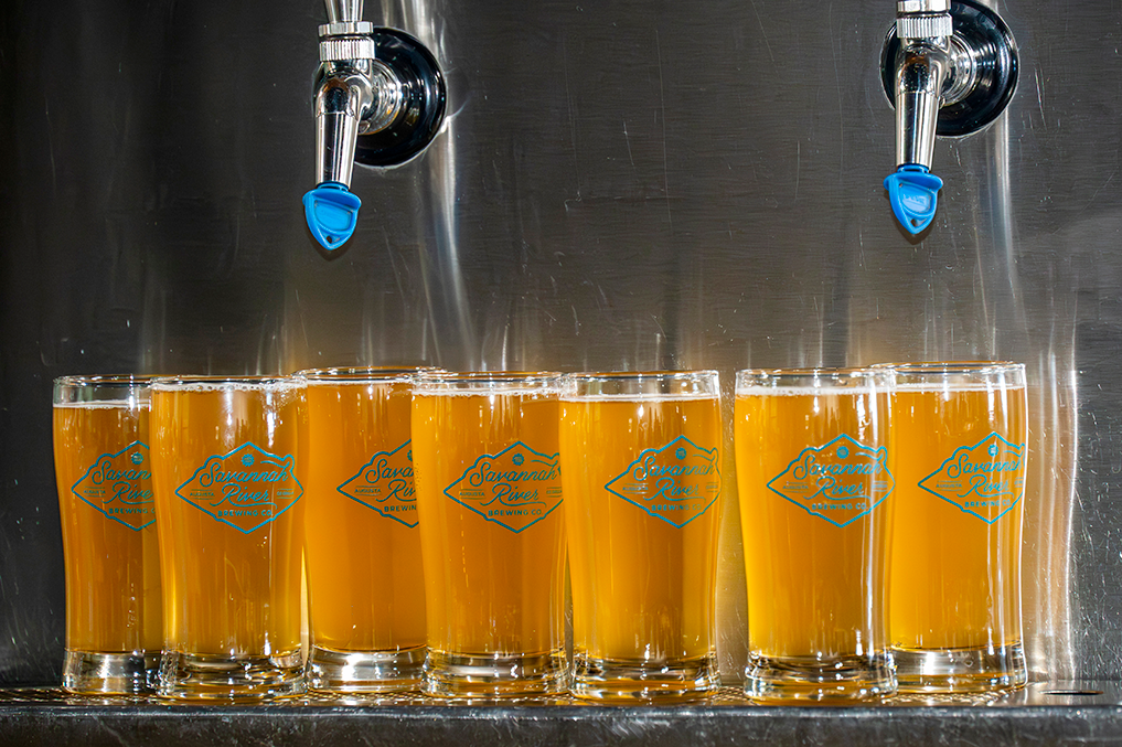 multiple glasses of beer under a tap