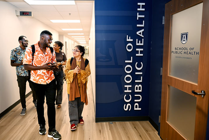A group of four students walk down a hallway.