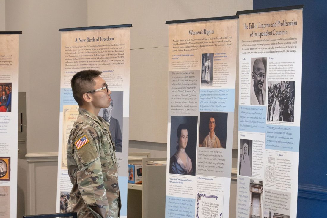 A student dressed in military gear reads a display about the history of democracy.
