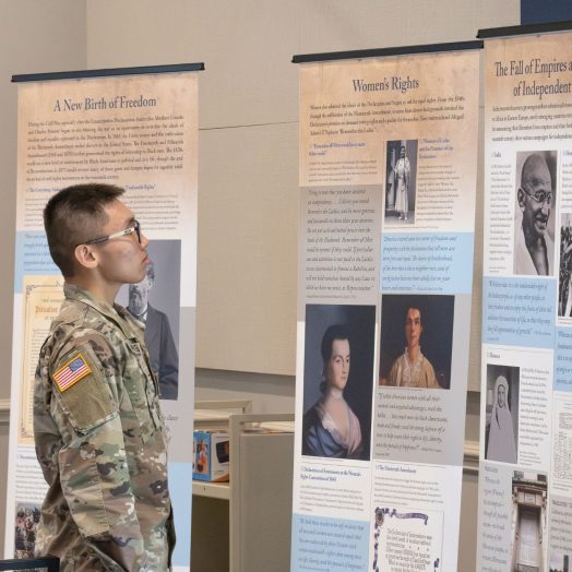 A student dressed in military gear reads a display about the history of democracy.