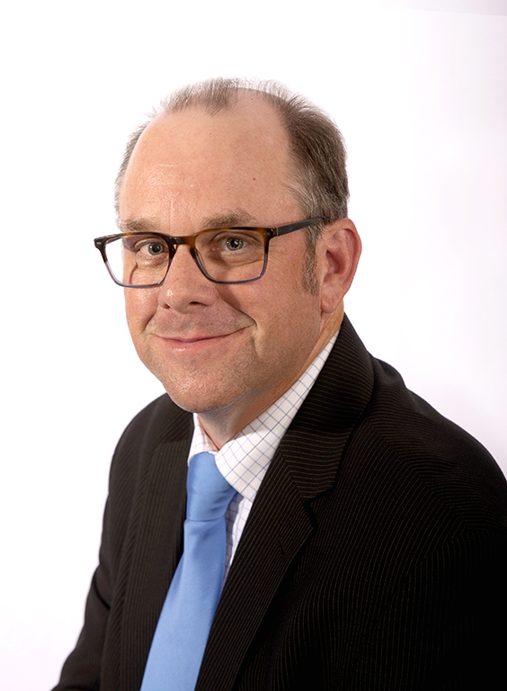Dr. Stan Dodson poses for headshot photo in front of white backdrop with suit and tie on.