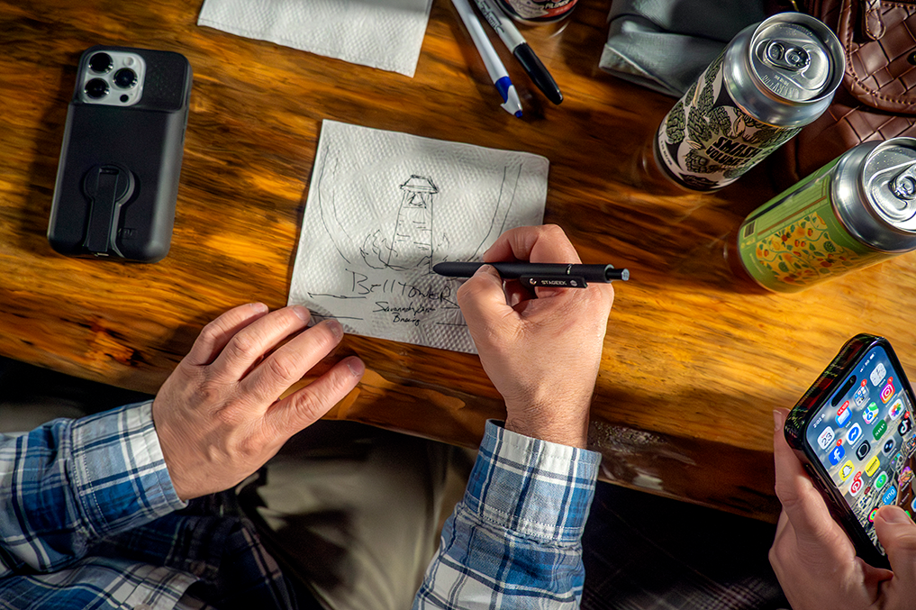 a man's hands drawing with a pen on a napkin