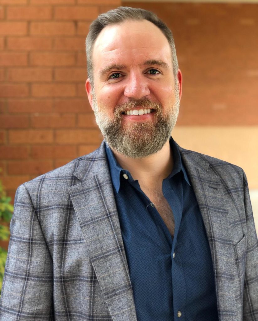 man wearing a plaid jacket smiling