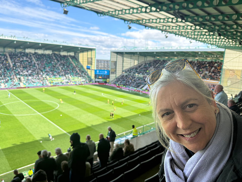 a woman's face with a game on a pitch behind her