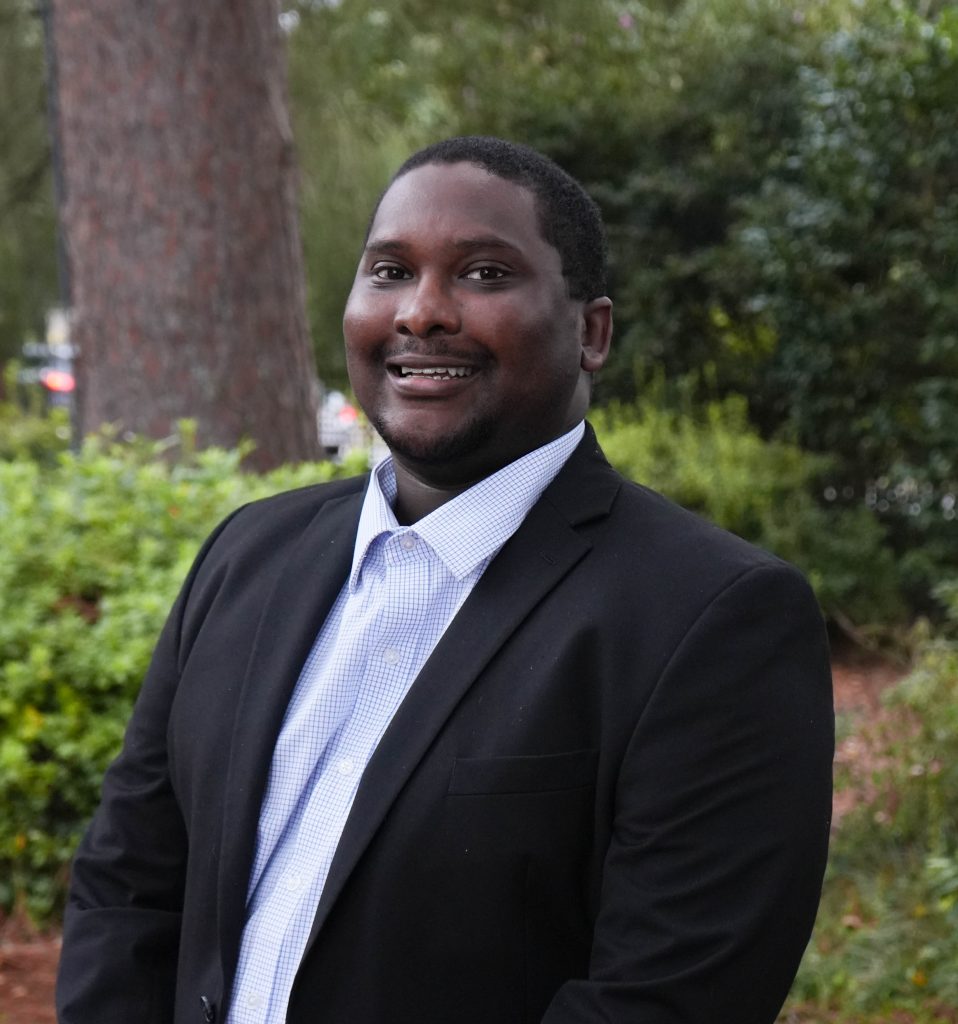 A middle-aged man smiles for a photo while standing outdoors