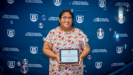 Female smiles as she holds her award