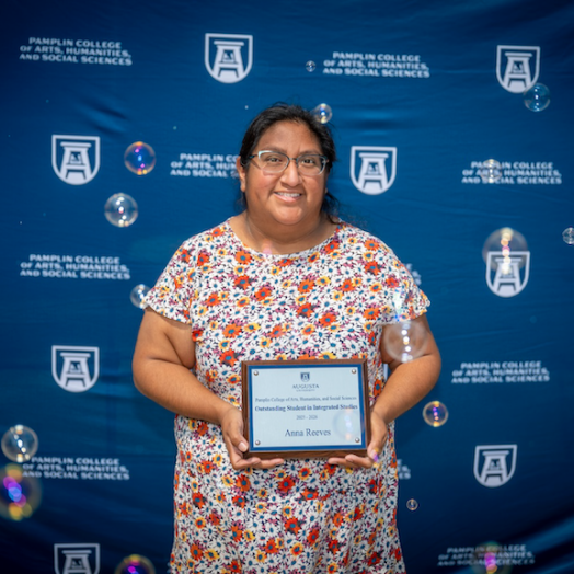 Female smiles as she holds her award