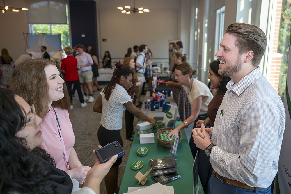 Students talking to man at a table