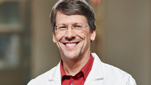 man in lab coat wearing glasses