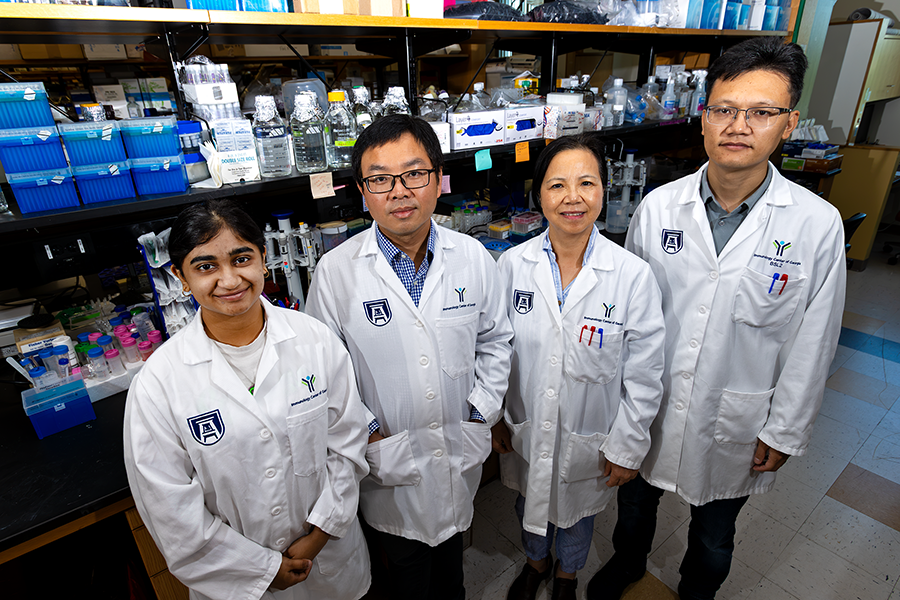 Four scientists stand in a scientific laboratory.